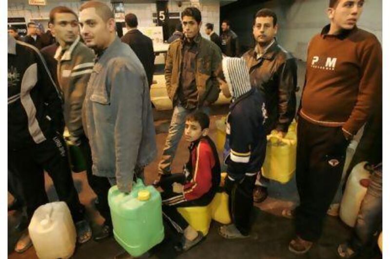 Palestinians wait to fill petrol in containers at a petrol station in Gaza.