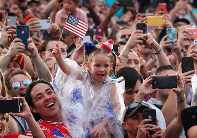 A child waves flags as people take photos while U.S. President Donald Trump and first lady Melania Trump arrive for the "Salute to America" event during Fourth of July Independence Day celebrations at the Lincoln Memorial in Washington, D.C., U.S., July 4, 2019. REUTERS/Carlos Barria