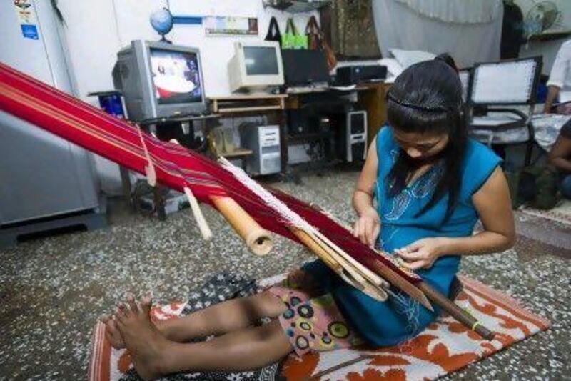 Muanpuii, a 35-year-old Burmese refugee from the Falam tribe in the Chin state of Burma, weaves using a hand loom in Vikaspuri, New Delhi.
