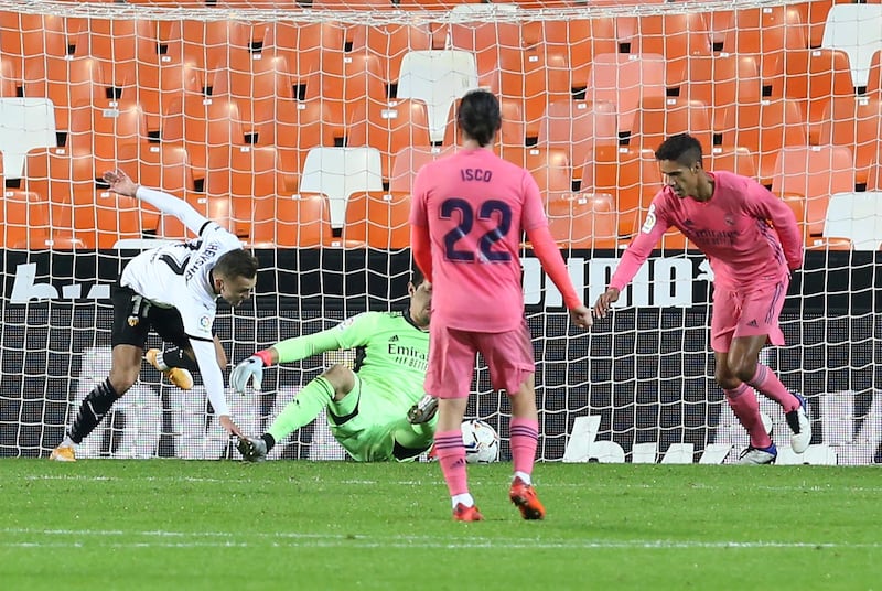 Real Madrid's Raphael Varane, right, scores an own goal past goalkeeper Thibaut Courtois to put Valencia ahead. AP