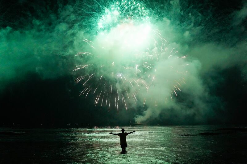 A man celebrates the start of the New Year watching fireworks explode over Santos Bay in Brazil. AP Photo