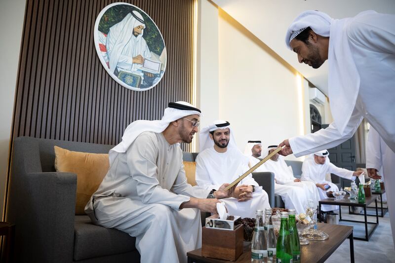 Sheikh Mohamed bin Zayed, Crown Prince of Abu Dhabi and Deputy Supreme Commander of the Armed Forces (L), looks at a picture during a visit to the home of Dr Omar Habtoor Al Derei, Director General of the UAE Fatwa Council (R).