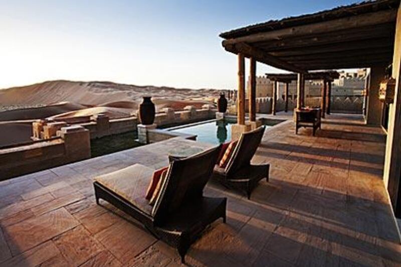 Rolling dunes stretch out to the horizon in front of one of the many villas at Qasr al Sarab Desert Resort.