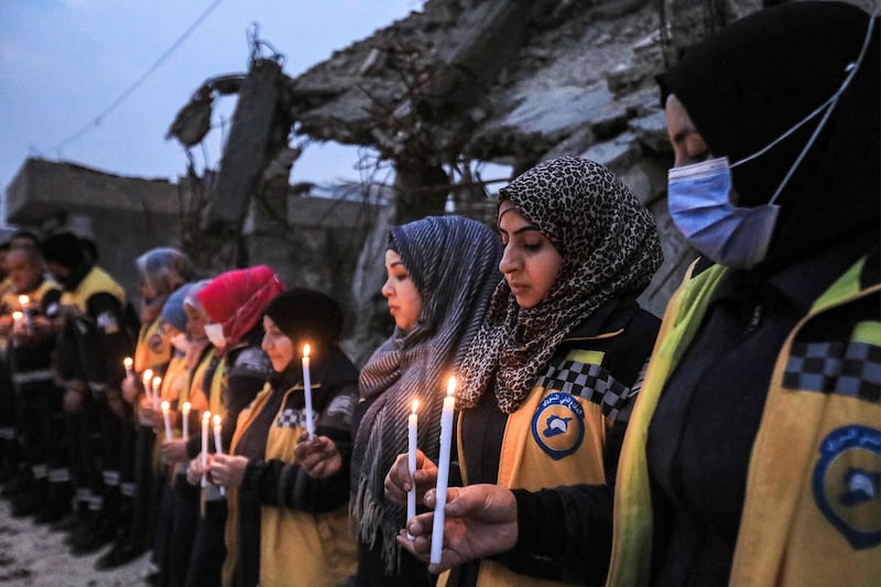Members of the Syrian Civil Defence (also known as the White Helmets) stand in a candle-lit remembrance vigil with survivors of the February 6, 2023 earthquake that devastated northern Syria and Turkey, marking the first anniversary of the disaster by some of the destroyed buildings in the town of Jindayris in the northwest of Syria's Aleppo province. AFP
