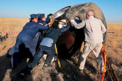 Russian Roscosmos specialists turn the Soyuz MS-12 space capsule shortly after the landing about 150 km (90 miles) south-east of the Kazakh town of Dzhezkazgan,  on October 3, 2019.  A three-man crew including an Emirati who became the first Arab to reach the International Space Station returned to Earth safely on October 3, 2019 and were in good shape, the Russian space agency Roscosmos said.

 / AFP / POOL / Dmitri Lovetsky

