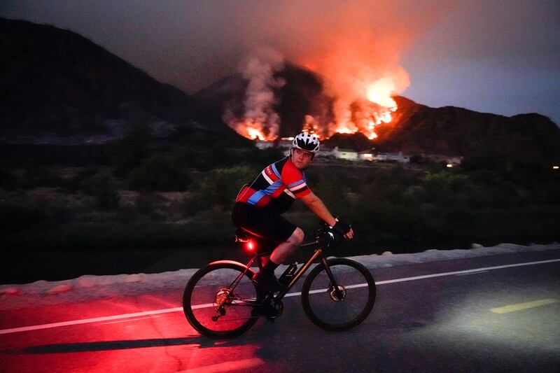 A cyclist rides along a trail as the ranch fire burns in California. AP