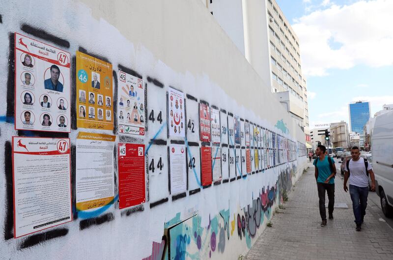 epa07895590 Tunisian people walk near posters of lists for the upcoming legislative elections in Tunis, Tunisia, 04 October 2019. The Parliamentary elections will be held on 06 October in Tunisia.  EPA/MOHAMED MESSARA
