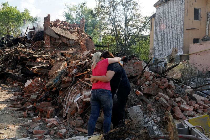 Women hug near the debris of a building that was destroyed after a rocket hit the Saltivka area in Kharkiv. EPA