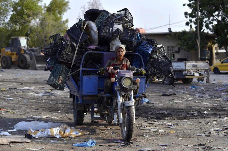 A young boy drives a small vehicle loaded with recyclable items at a landfill site in the Iraqi holy city of Najaf. AFP