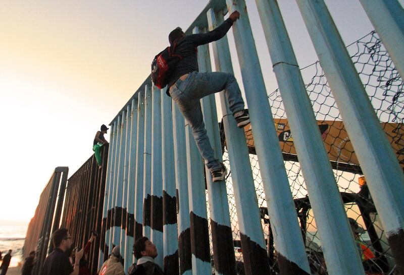 epa07166202 Migrants from a caravan of Central Americans mainly from Honduras congregate on the border fence in Tijuana, Mexico, 14 November 2018. Approximately 800 Central American migrants arrived in the Mexican border city of Tijuana to seek asylum in the United States, and by Friday 2,000 more migrants are expected to arrive in Tijuana by bus.  EPA/JOEBETH TERRIQUEZ