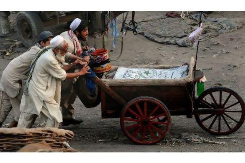 Vendors push a hand cart in Lahore. The IMF says Pakistan needs to improve debt management and broaden its tax base. Arif Ali / AFP