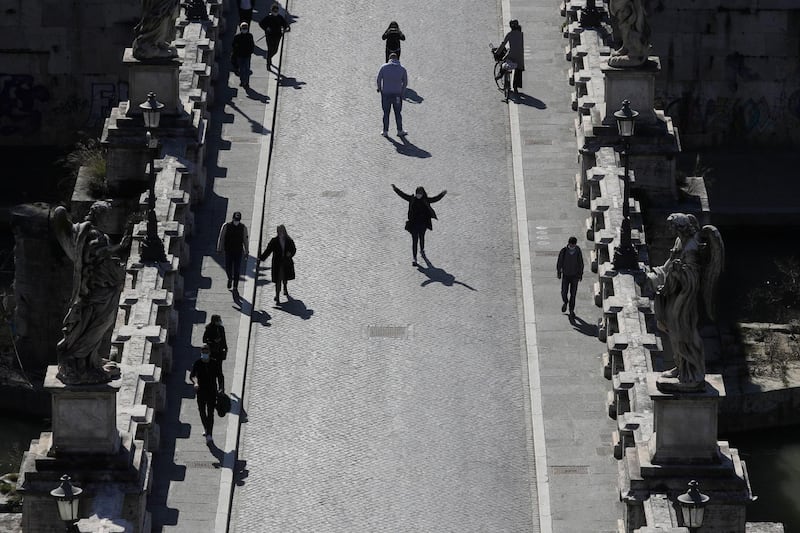 People stroll along the Sant'Angelo bridge in Rome, Italy. AP Photo