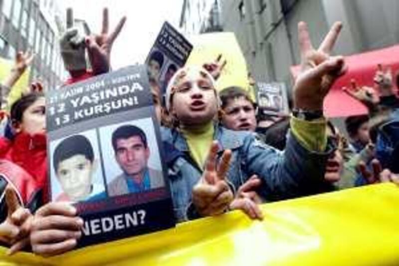 A Kurdish boy holds poster of Ugur Kaymaz (L) and Ahmet Kaymaz (R) and flash victory signs during a demonstration in Istiklal avenue, downtown Istanbul, 20 February 2005. A group of Kurdish children gathered  at Istiklal avenue to protest the killing of Ugur Kaymaz,12, and his father Ahmet Kaymaz, 34, in front of their house by Turkish security forces on 21 November 2004 at Mardin, in Kiziltepe, southeastern Turkey. AFP PHOTO/Mustafa Ozer