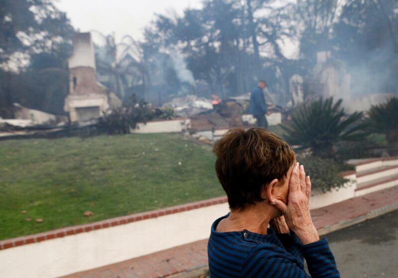 A woman cries as she covers her face near her destroyed home a wildfire swept through Ventura, California. Daniel Dreifuss via AP