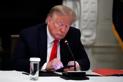 Donald Trump looks at his phone in the State Dining Room of the White House in Washington. AP