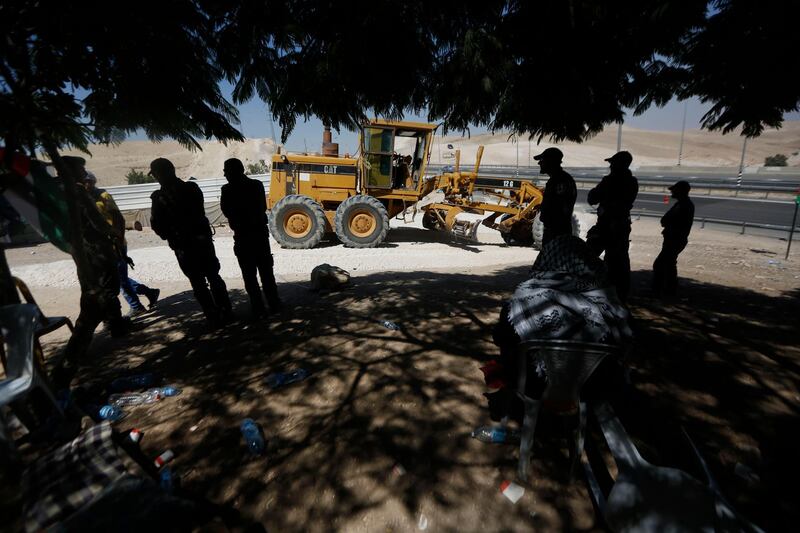 Palestinians watch as an Israeli bulldozer works in the West Bank hamlet of Khan al-Ahmar, Thursday, July 5, 2018. The Bedouin village outside the Kfar Adumim settlement, is set to be demolished on an unknown date after Israel's Supreme Court approved the move in May. (AP Photo/Majdi Mohammed)