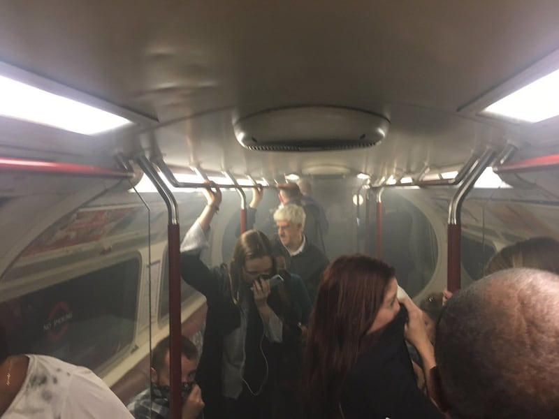 In this photo provided by Joe Bunting, commuters cover their mouths as smoke fills the carriage of a Bakerloo line train, near Oxford Circus in London, Friday, Aug. 11, 2017. One of the busiest stations on London's subway system was evacuated Friday morning after a train carriage filled with smoke. London Fire Brigade said crews were investigating "smoke issuing at platform level" at Oxford Circus station. (Joe Bunting via AP)
