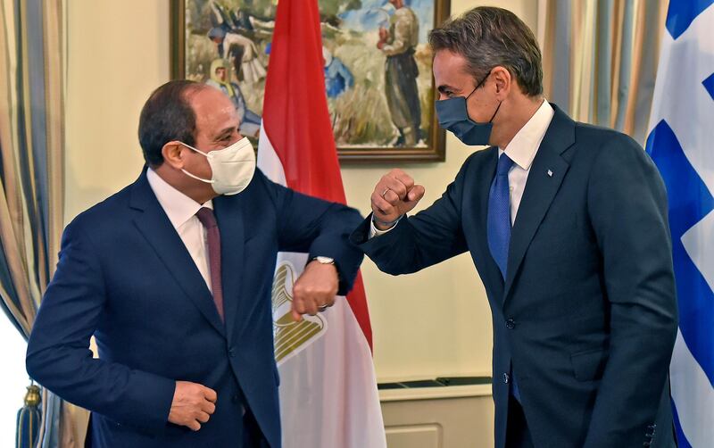 epa08761322 Egyptian President Abdel Fattah al-Sisi (L) shares an elbow bump with Greek Prime Minister Kyriakos Mitsotakis (R), both mask-clad due to the COVID-19 coronavirus pandemic, as they meet at the presidential palace in Nicosia, Cyprus 21 October 2020. Al-Sisi is in Cyprus for the 8th Trilateral Summit between Cyprus, Greece and Egypt.  EPA/IAKOVOS HATZISTAVROU / POOL