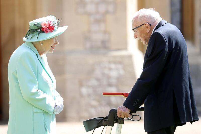 Britain's Queen Elizabeth II awards Captain Tom Moore with the insignia of Knight Bachelor at Windsor Castle in 2020. Reuters