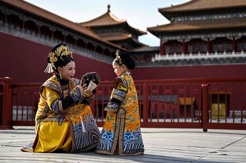 A woman and girl in traditional Chinese costume chat at the Forbidden City during a photo session in Beijing. AFP