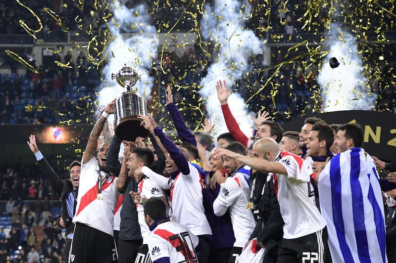 River Plate players celebrate with the trophy after winning the second leg match of the all-Argentine Copa Libertadores final against Boca Juniors, at the Santiago Bernabeu stadium in Madrid. AFP/Javier SORIANO