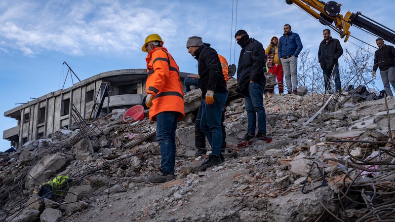 Rescuers search for signs of life at the site of a collapsed building