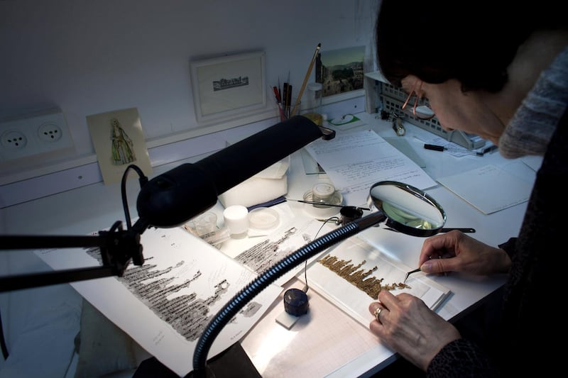 JERUSALEM, ISRAEL - DECEMBER 18:  (ISRAEL OUT) A conservation analyst from the Israeli Antiquities department examines fragments of the 2000-year-old Dead Sea scrolls at a laboratory before photographing them on December 18, 2012 in Jerusalem, Israel.  More than sixty years after their discovery Israel have put 5,000 fragments of the ancient Dead Sea scrolls online in a partnership with Google. (Photo by Uriel Sinai/Getty Images)