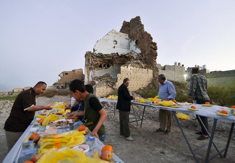 TOPSHOT - Iraqis share a collective iftar, the evening meal that will end the daily fast at sunset, on the second day of the Islamic holy month of Ramadan, in the war-ravaged old part of the northern city of Mosul, on April 15, 2021.   / AFP / Zaid AL-OBEIDI
