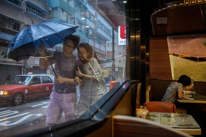 A couple walk in the heavy rain as a woman sits in a restaurant as Typhoon Haima makes landfall in Hong Kong. The usually frenetic streets of Hong Kong were deserted as the city went into lockdown for Typhoon Haima, which has killed at least eight people in the Philippines. Anthony Wallace / AFP