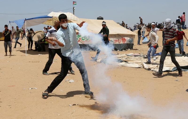 A demonstrator uses a tennis racket to hit back a tear gas canister fired by Israeli soldiers.  Ibraheem Abu Mustafa / Reuter