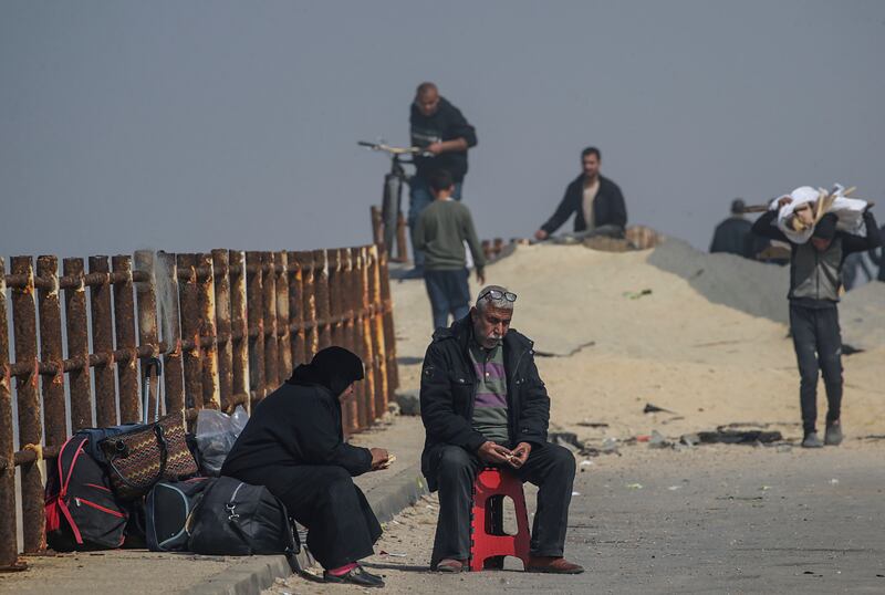 Palestinians rest along the road after crossing from the northern Gaza Strip into the south of Gaza city. EPA