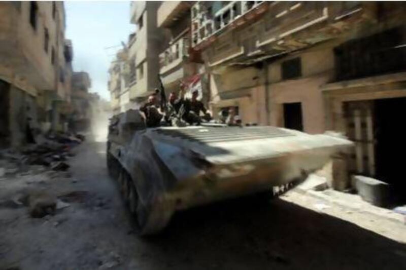 Syrian government forces patrol in a tank in a previously rebel-held district in Homs.