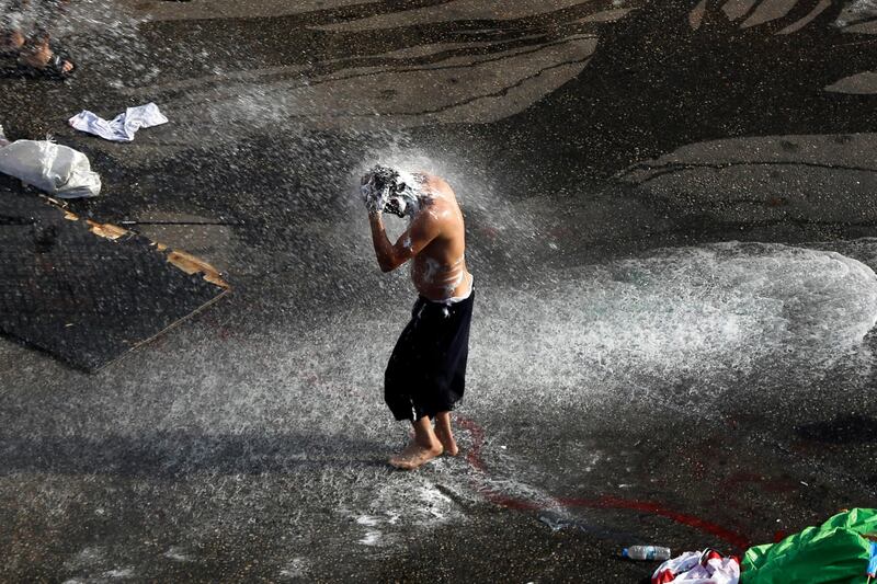 An anti-government protester takes a shower after he asked a riot police to spray him by water cannon, where protesters have been gathering for four weeks, in front of the government palace in Beirut, Lebanon. AP Photo