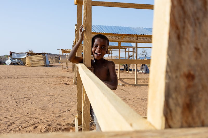 A young Sudanese refugee reacts while playing inside a shelter under construction in the Farchana refugee camp