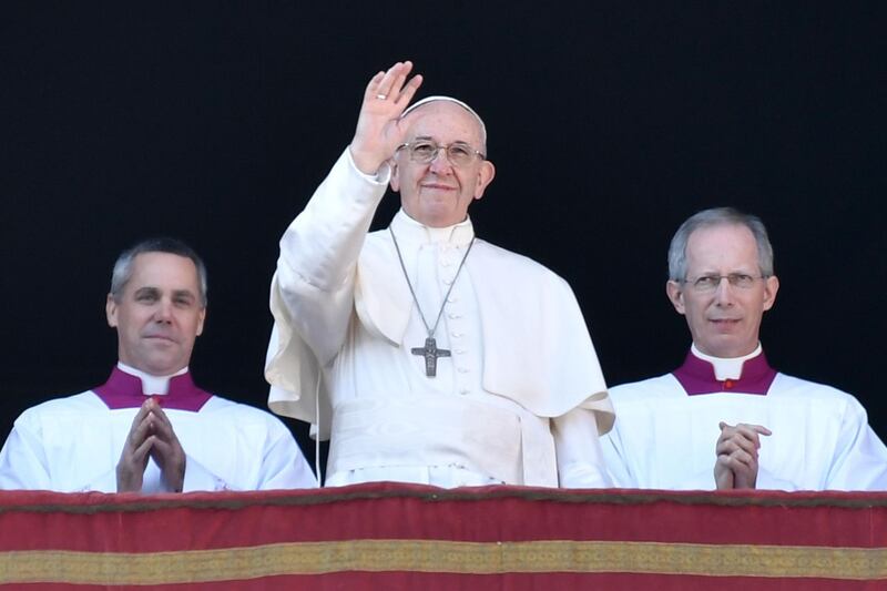 Pope Francis waves from the balcony of St Peter's basilica during the traditional "Urbi et Orbi" Christmas address and blessing given to the city of Rome and to the World. AFP PHOTO / Andreas SOLARO