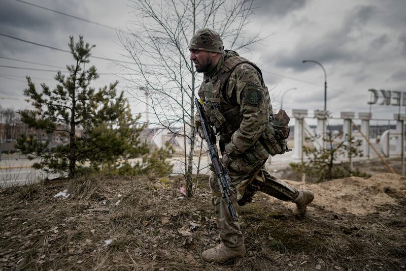 A Ukrainian serviceman approaches vehicles in Irpin, on the outskirts of Kyiv. AP Photo / Vadim Ghirda