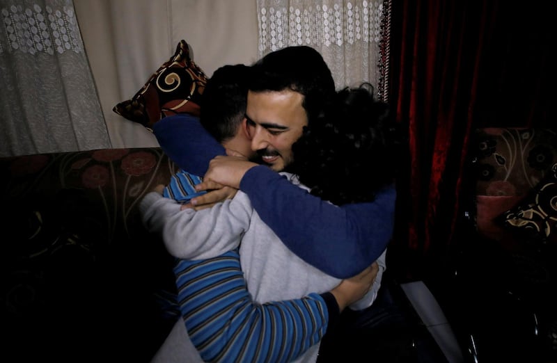 Amjad Yaghi hugs his younger brothers as he reunites with his mother. Reuters