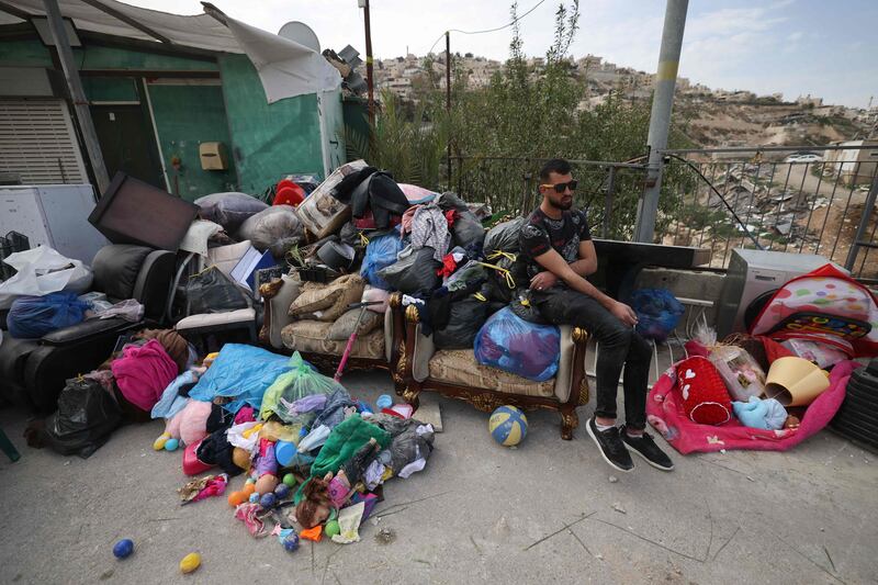 A Palestinian man sits next to the belongings of Rateb Hatab Shukairat, after the house in East Jerusalem was demolished by Israeli bulldozers. AFP