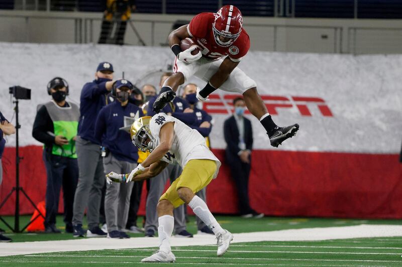 Alabama running back Najee Harris (22) hurdles Notre Dame cornerback Nick McCloud (4) as he carries the ball for a long gain in the first half of the Rose Bowl NCAA college football game in Arlington, Texas, Friday, Jan. 1, 2021. (AP Photo/Michael Ainsworth)