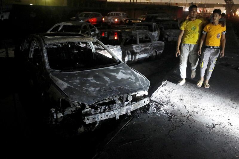 People walk past burned vehicles following a fire that broke out in Egypt's Shuqair-Mostorod crude oil pipeline, at the beginning of Cairo-Ismailia road, Egypt. REUTERS