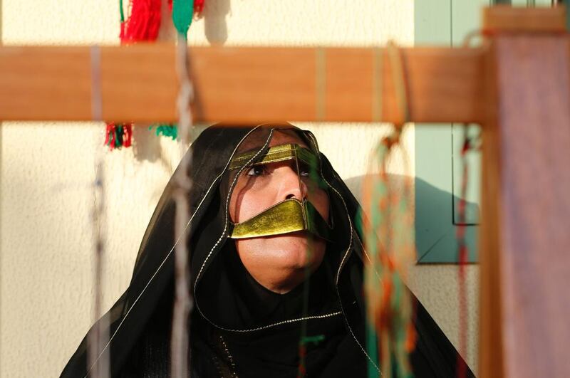 An Emirati woman works on a weaving loom.