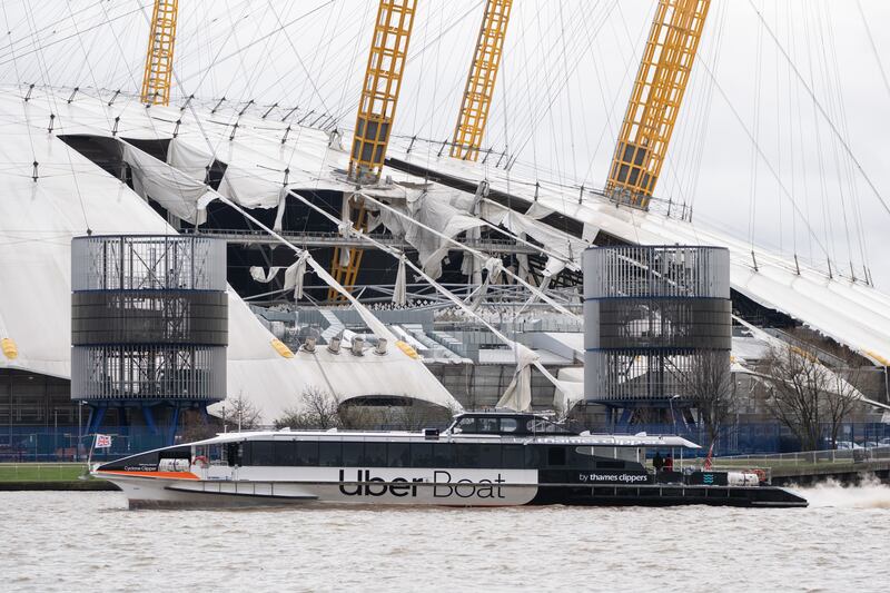 A Thames clipper sails past the O2 Arena in London, after parts of its roof were ripped off in high winds as Storm Eunice struck. PA