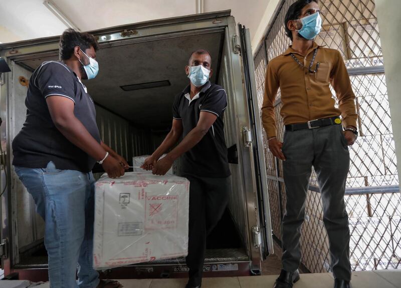 A Sri Lankan health services workers unload a consignment of Oxford-AstraZeneca vaccine donated by the Indian government at a medical warehouse as a plain clothed police officer stands guard in Colombo, Sri Lanka.  AP Photo
