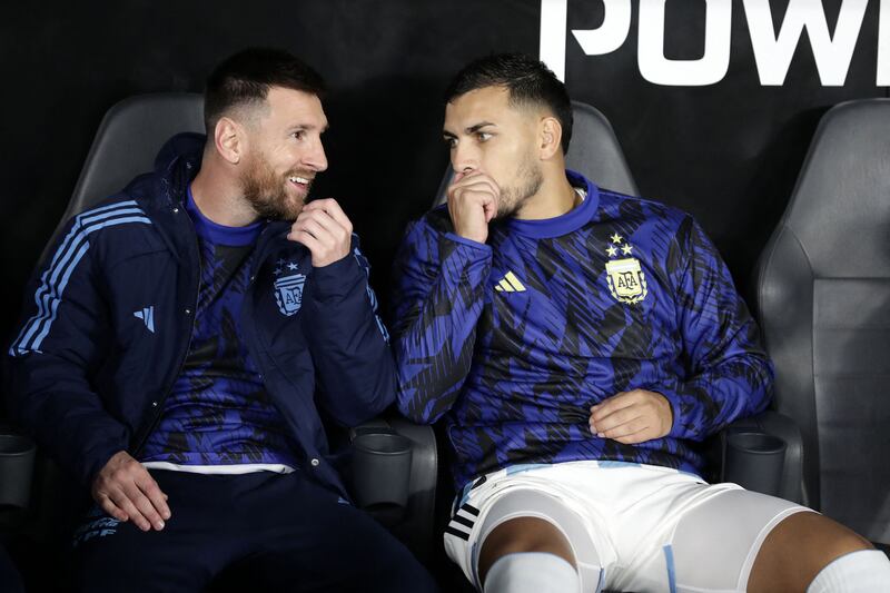 Argentina forward Lionel Messi teammate Leandro Paredes speak on the bench. AFP