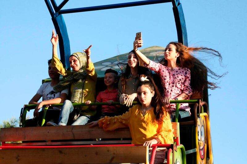 Palestinian youths react as they ride a swing boat in the village of Tarqumia, north the West Bank town of Hebron. AFP