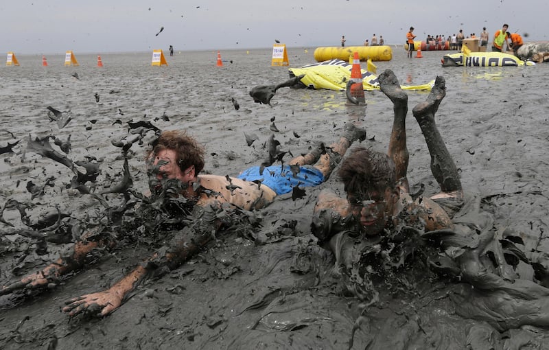 Men slide in the mud during the Boryeong Mud Festival. The 20th annual mud festival features mud wrestling and mud sliding. Ahn Young-joon.