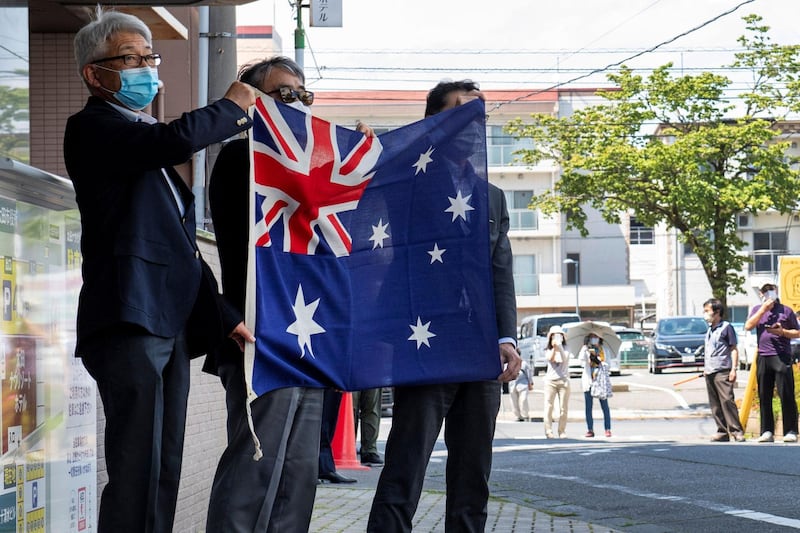 Hotel staff greet the Australian softball national team with the Australian national flag at a hotel in Ota City, Gunma prefecture. AFP