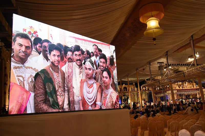 Indian mining tycoon Gali Janardhan Reddy, centre, is seen on a big screen as he poses with his daughter Bramhani, second from right, and his son-in-law Rajeev Reddy, second from left, during their lavish wedding at the Bangalore Palace Grounds in Bangalore, Karnataka in December 2016. AFP Photo