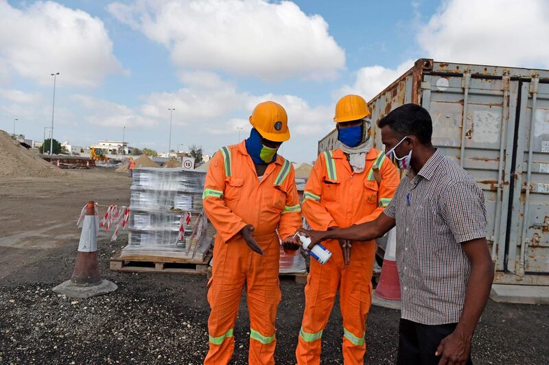 Expatriated workers carrying out road project development sanitise their hands as they shift between work sites in Aali village. AFP