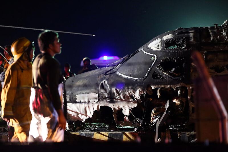 Rescuers stand next to the wreckage of a Westwind aircraft after it caught on fire during takeoff at Manila international airport in Manila.  AFP